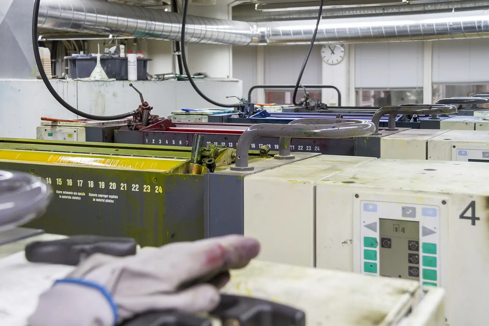Four-colour sheetfed offset printing press with an operator's hand on the control unit